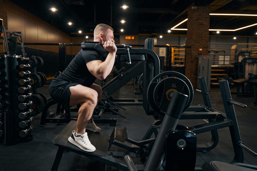 Male athlete doing leg exercise using gym equipment